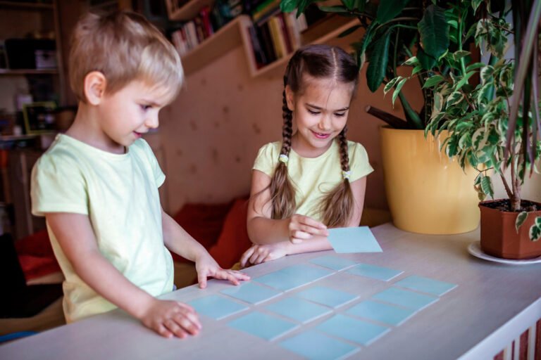 two smiling kids playing a memory game together at home, focused and happy