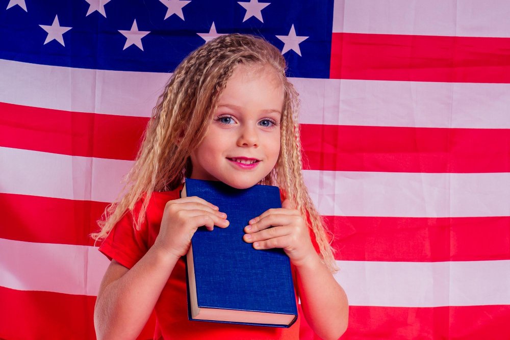 Girl holding a book in front of the American flag on Independence Day