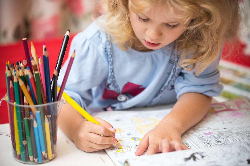 Child colouring with crayons