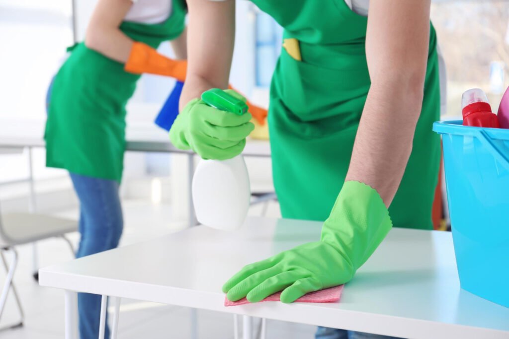 Professional cleaner using EPA-certified spray to disinfect school desks